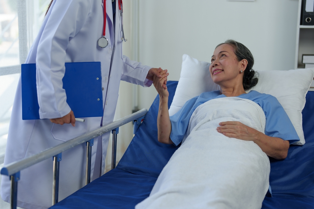Doctor Comforting Elderly Patient in Hospital Bed - Pre-Operative Care A doctor holds the hand of an elderly woman lying in a hospital bed, offering comfort and care - Pre-Operative Care